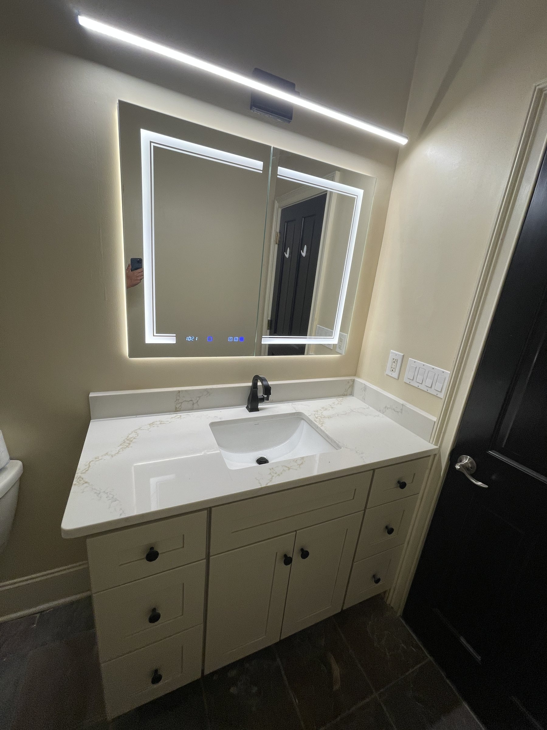 Finished bathroom vanity, countertop, faucet, mirror, and lighting installed by Only Solutions